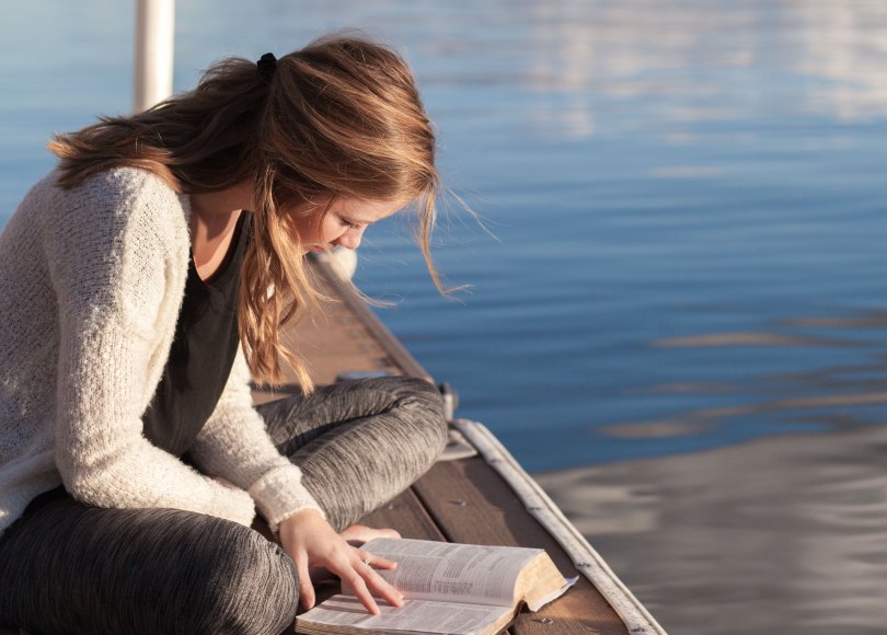 Woman reading her Bible on a dock