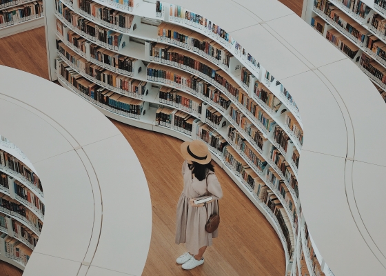 Woman looking through rows of books in a library